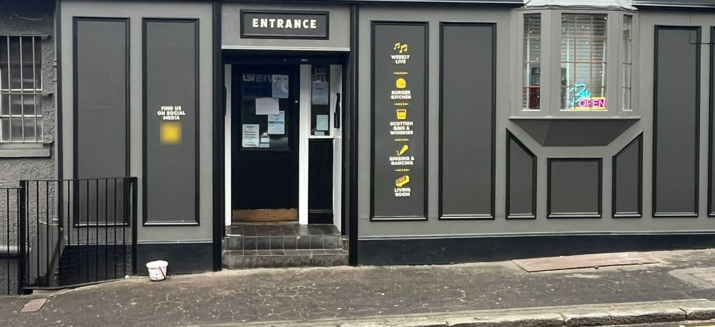 A bar front painted charcoal, with black-lined panels