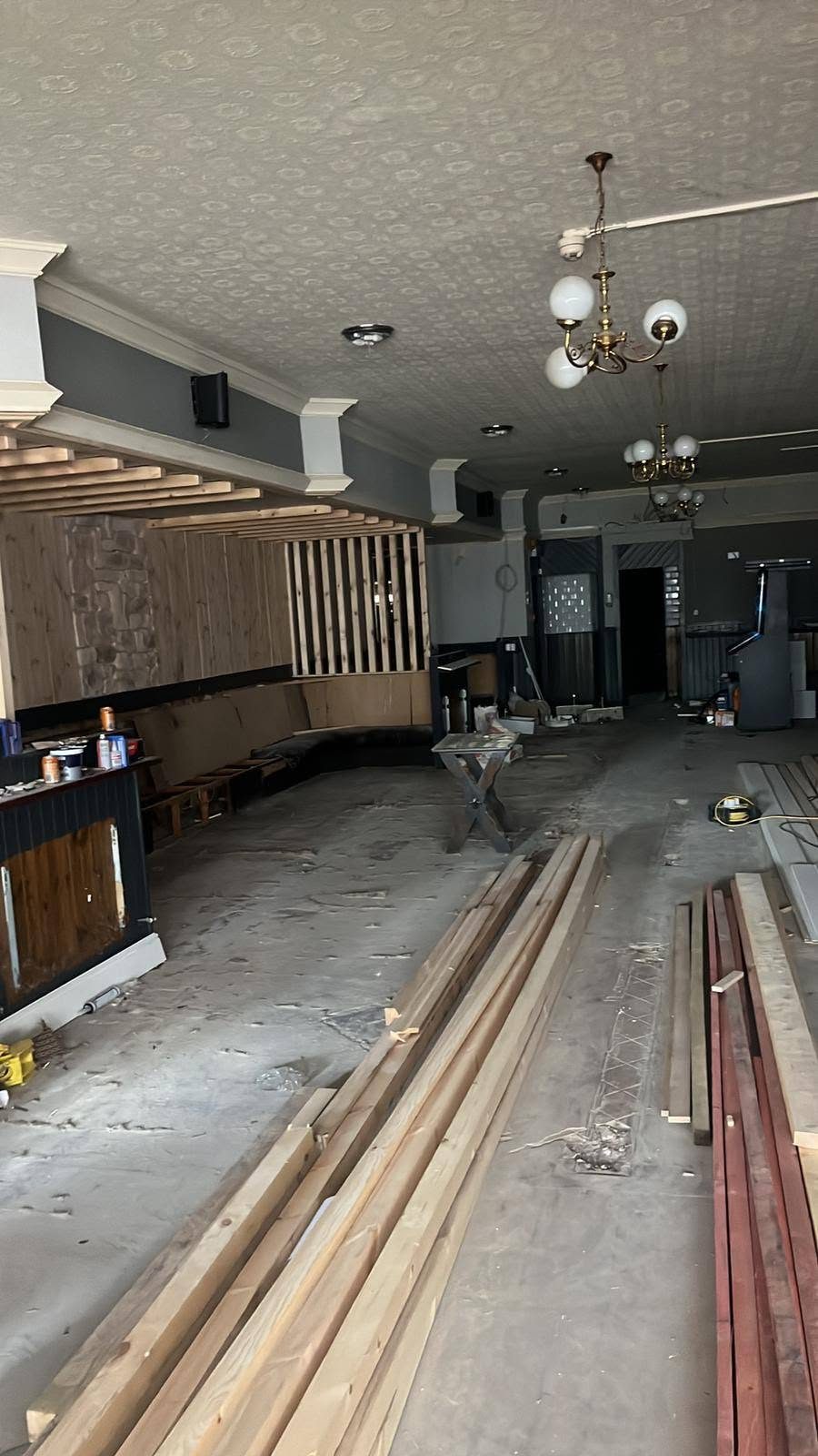Before: a bar lounge mid strip-out, with bare floor and stacked timber