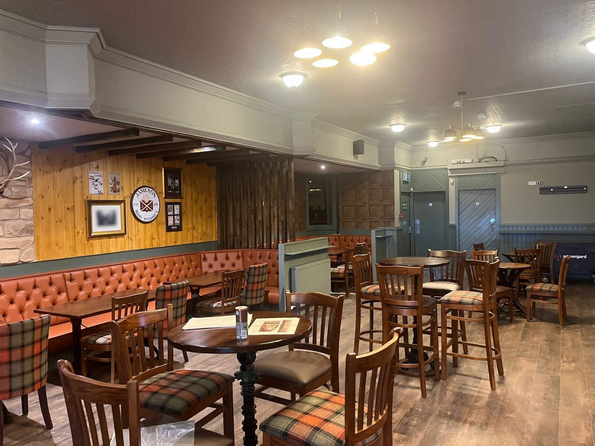 After: the same lounge finished, with sage paintwork, a pale ceiling, banquettes and high tables