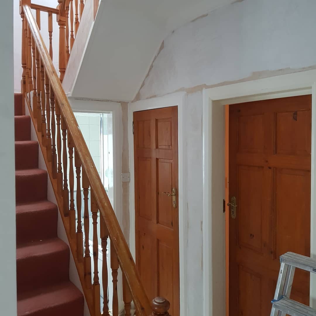 Before: a hall under the stairs with new plaster on the walls and ceiling