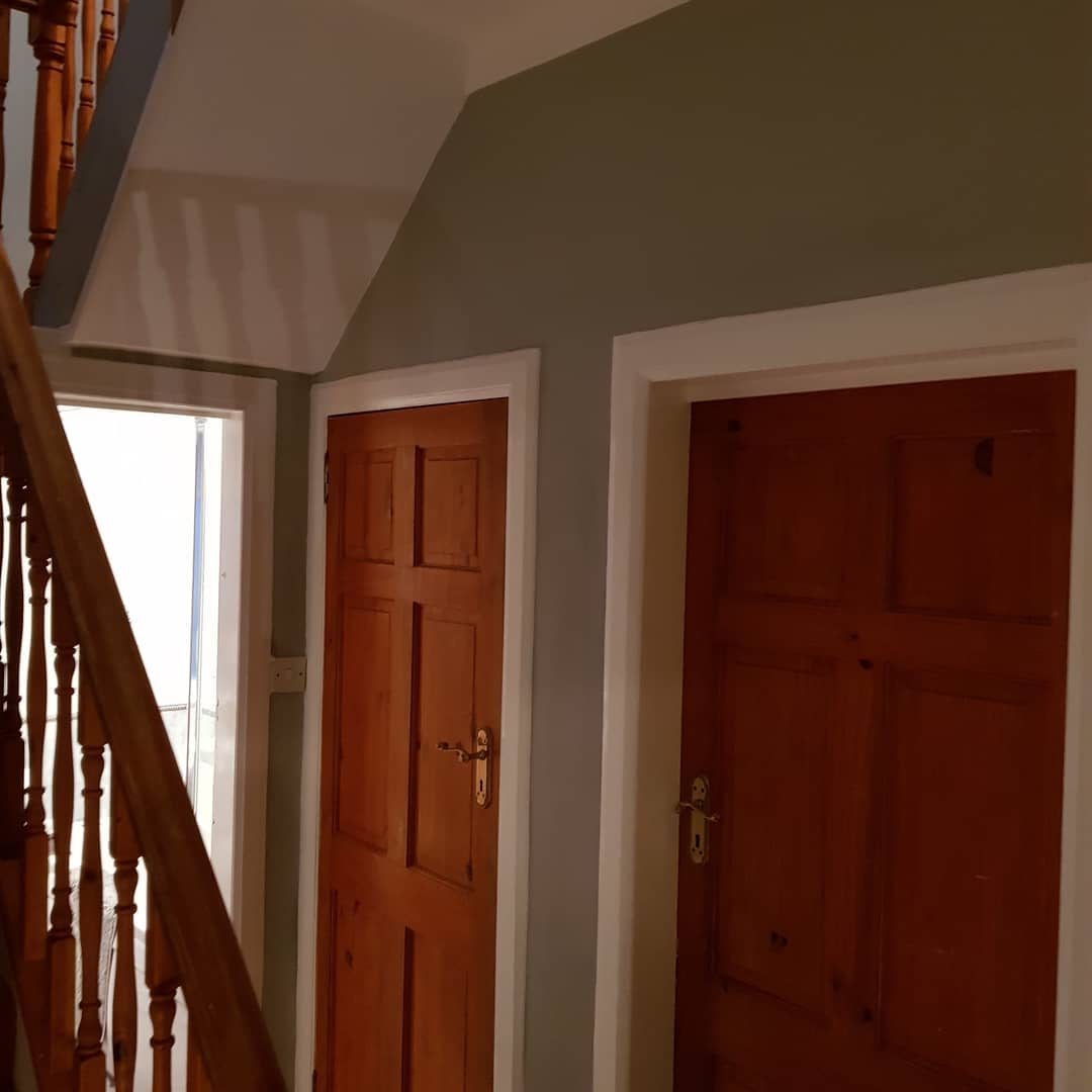 After: the same hall with sage walls, a white ceiling and white gloss facings and skirtings