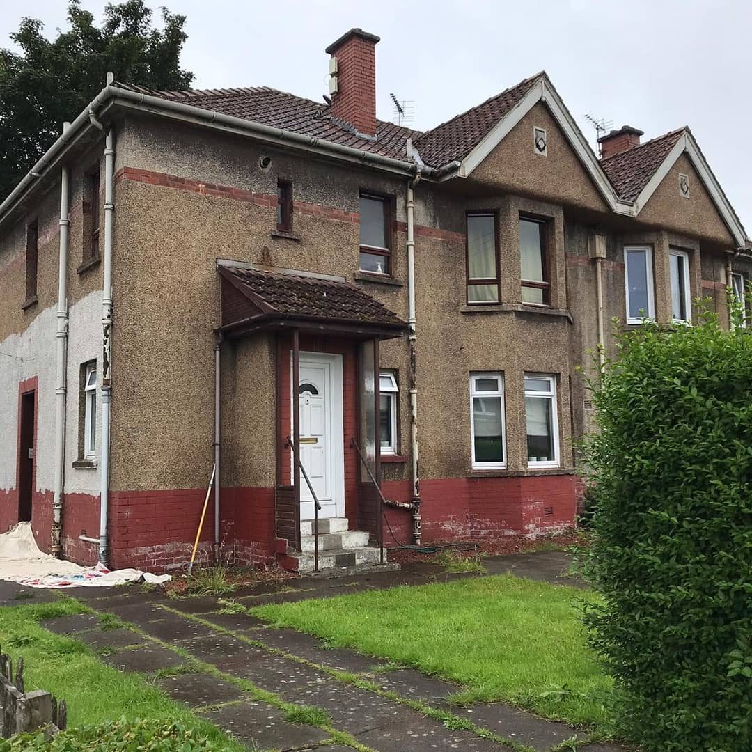 Before: a pebbledash semi with red-painted brick, work just started at the gable