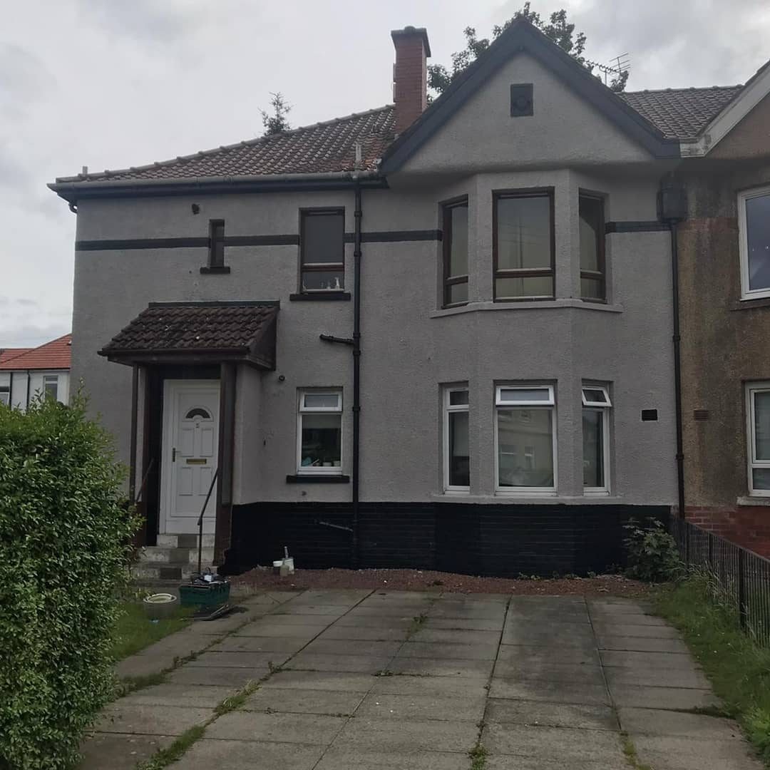 After: the same house painted light grey, with a black band and base