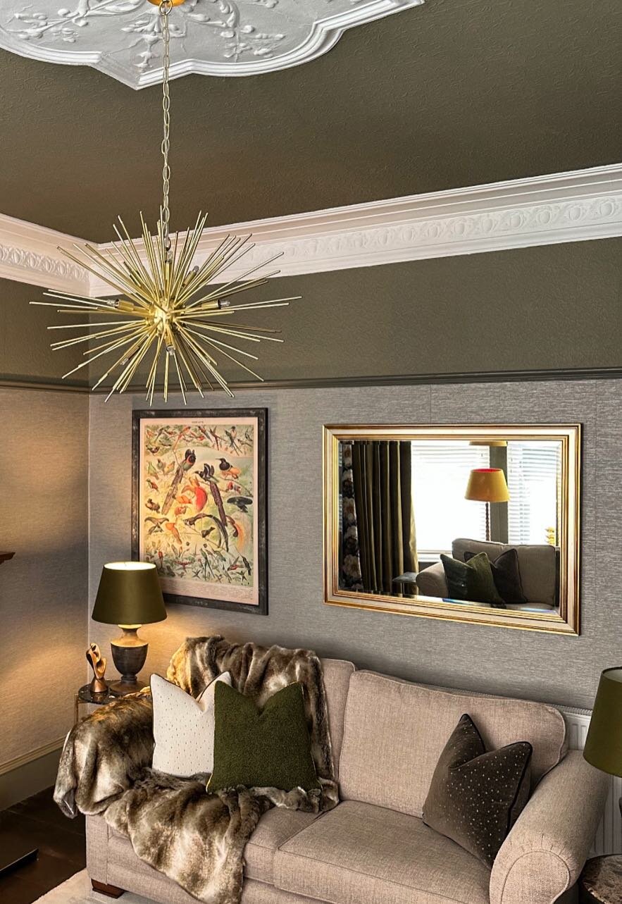 A sitting room with a grey textured paper on the lower walls, under olive upper walls and a white cornice