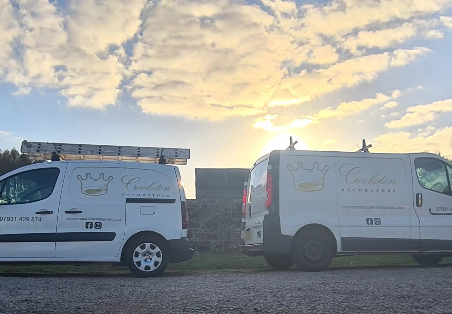 Two white vans in a gold crown livery, parked under a sunset sky